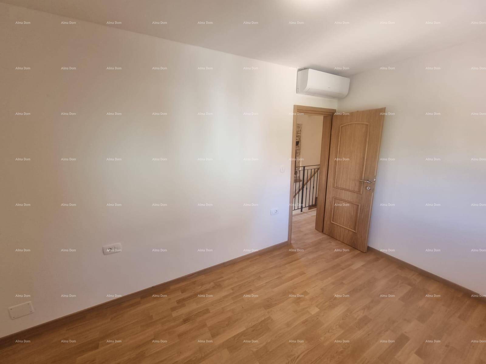 Leeres Schlafzimmer mit Holzboden, weiß gestrichenen Wänden und Klimaanlage.