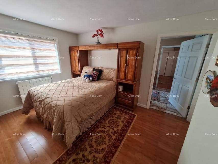 Helles Schlafzimmer mit Holzboden, integriertem Bettrahmen und Fenster mit Jalousien.