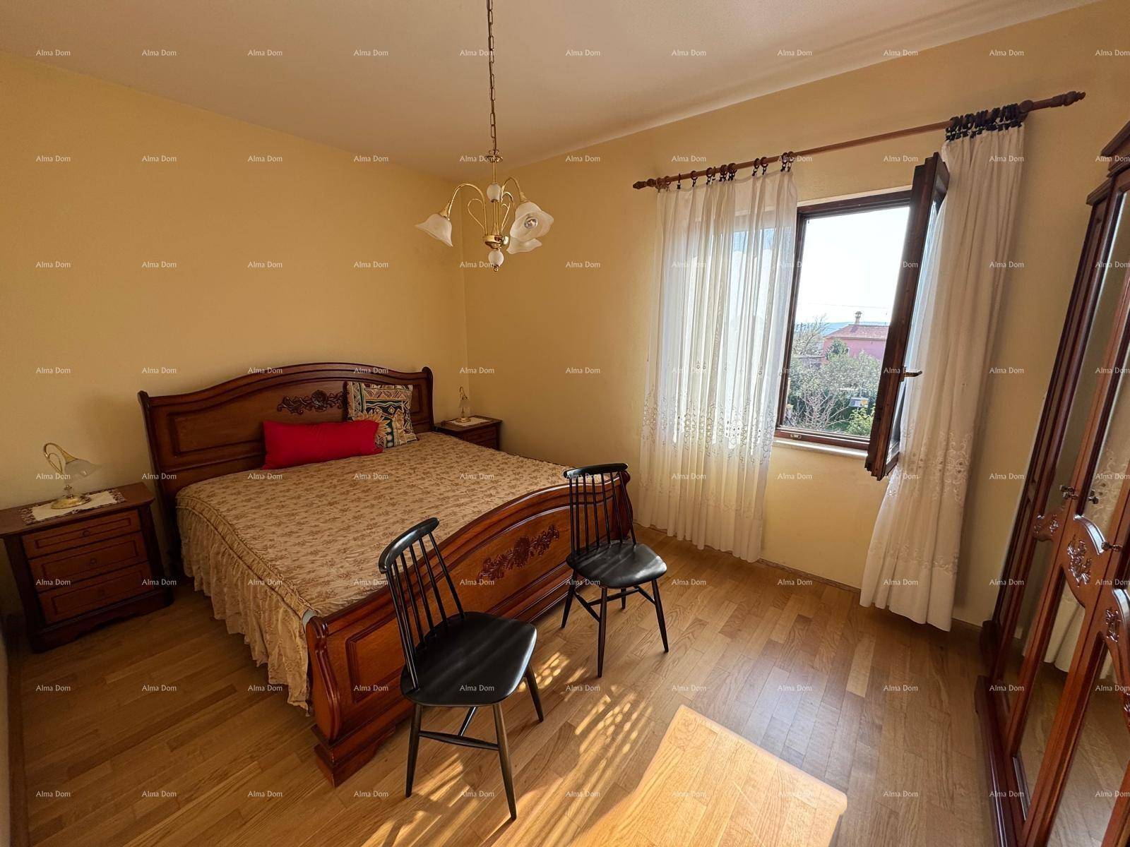 Schlafzimmer mit Doppelbett, Holzmöbeln und Parkettboden, mit Blick nach draußen.