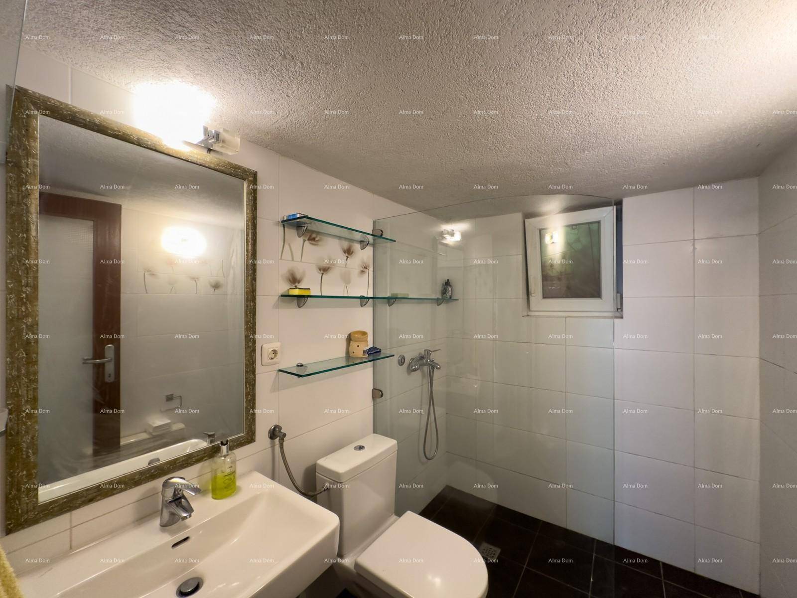 Badezimmer mit weißen Wandfliesen, dunklem Boden, Dusche, WC und einem Fenster.