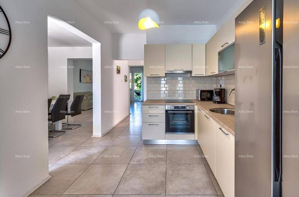 Moderne Küche mit beigen Schränken, Fliesenboden und Blick in den Essbereich.