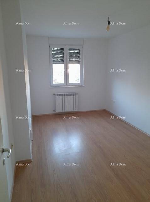 Schlafzimmer mit Holzboden, weiß gestrichenen Wänden und einem Fenster mit Heizkörper darunter.