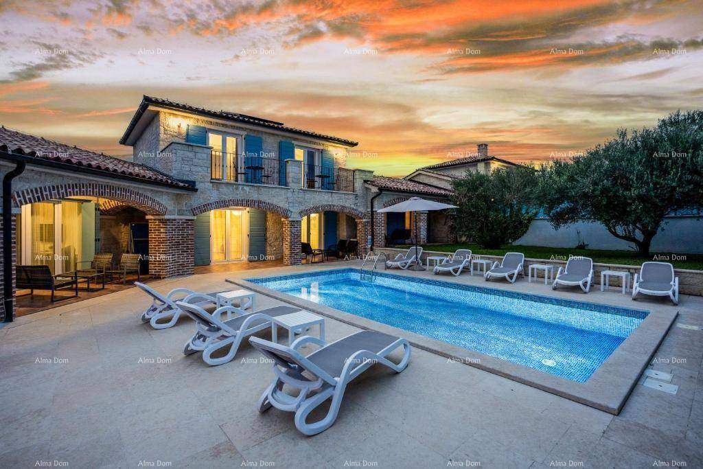 Elegante Villa mit großem Poolbereich und Sonnenliegen bei malerischem Sonnenuntergang.
