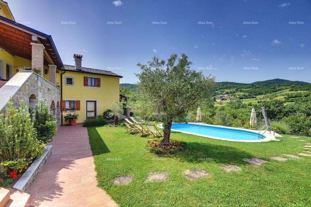 Seitlicher Blick auf die gelbe Villa mit Steinfassade und den gepflegten Garten mit Pool und Terrasse.