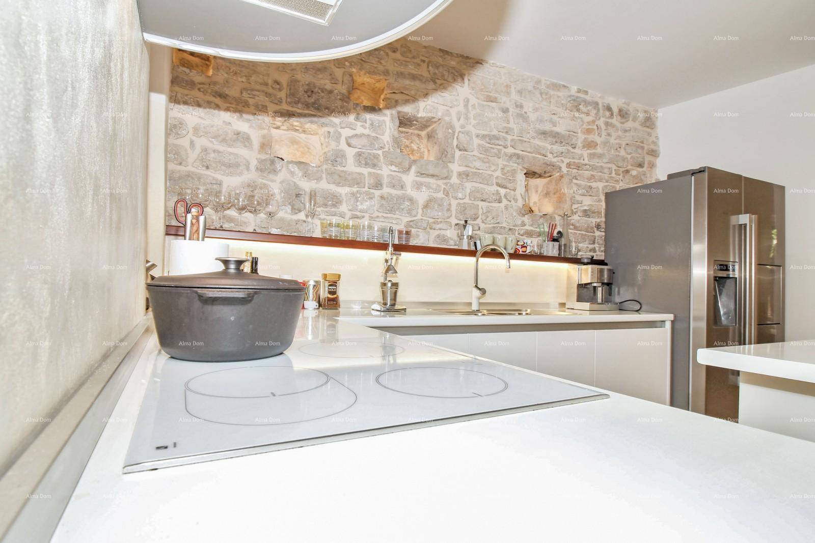 Induktionskochfeld auf der Kücheninsel in einer modernen Küche mit Steinwand und Unterbauleuchten.