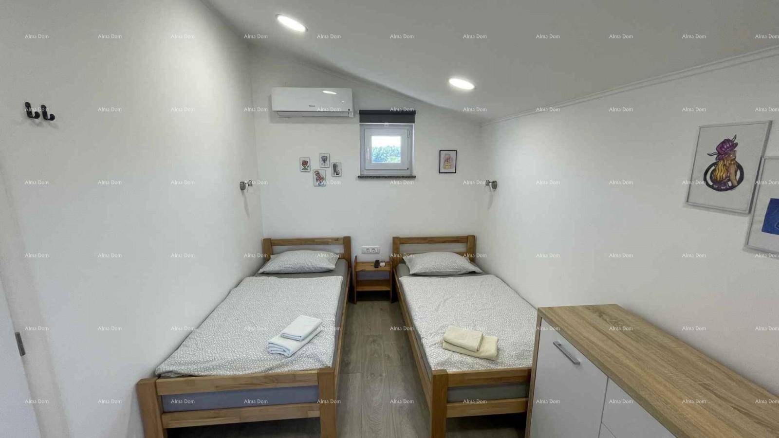 Helles Schlafzimmer mit zwei Einzelbetten, Klimaanlage und Holzböden.