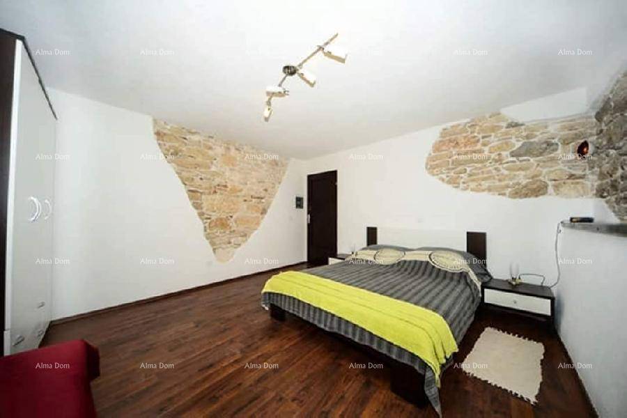 Schlafzimmer mit Doppelbett, Holzboden und dekorativen Steinwänden, die Charakter verleihen.