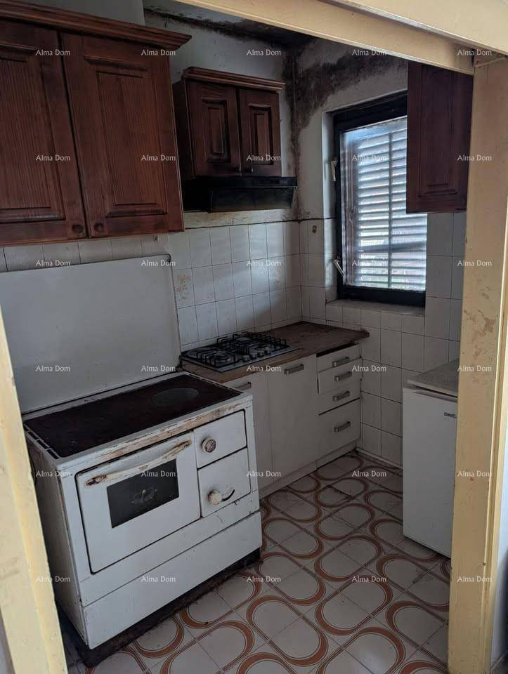 Kleine, traditionelle Küche mit Holzofen, Gaskochfeld, Spüle und Kühlschrank, mit Fliesenboden.