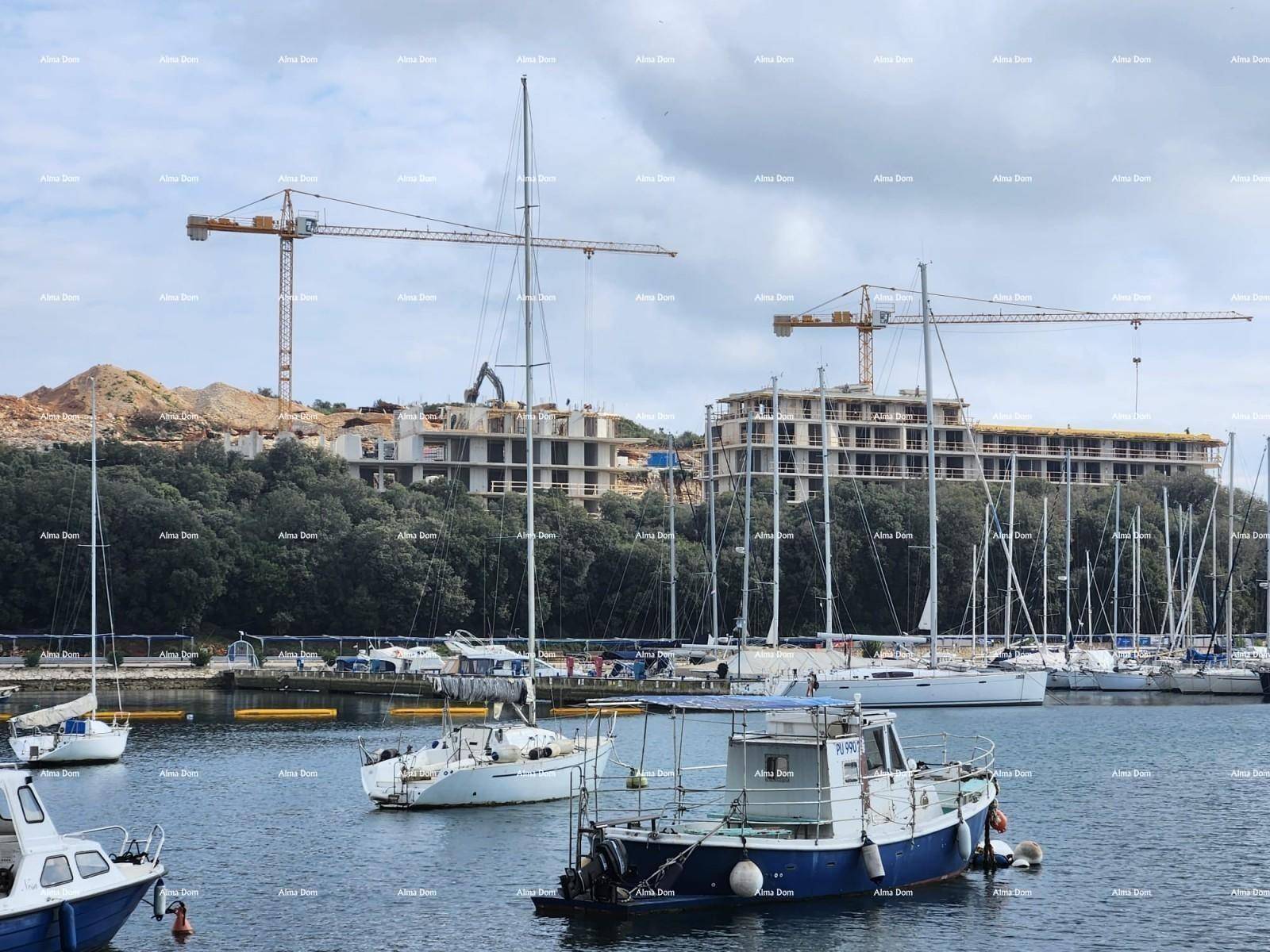 Nahaufnahme eines Yachthafens mit Segelbooten und einer aktiven Baustelle mit Kränen.