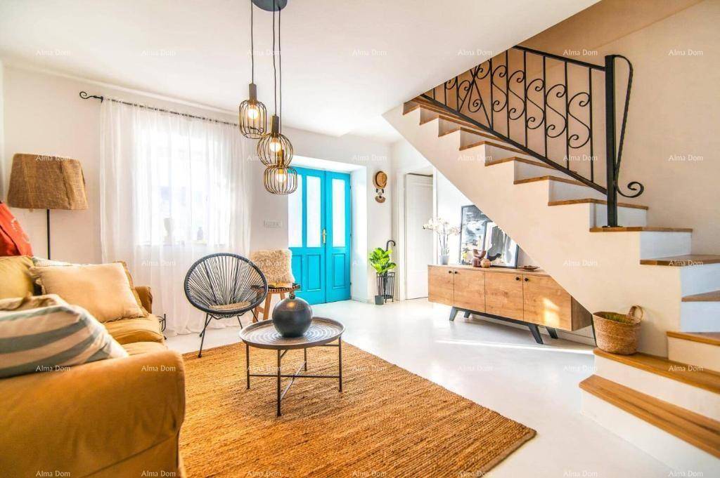 Gemütliches Wohnzimmer mit bequemer Couch, Teppich und einer Treppe mit schmiedeeisernem Geländer.