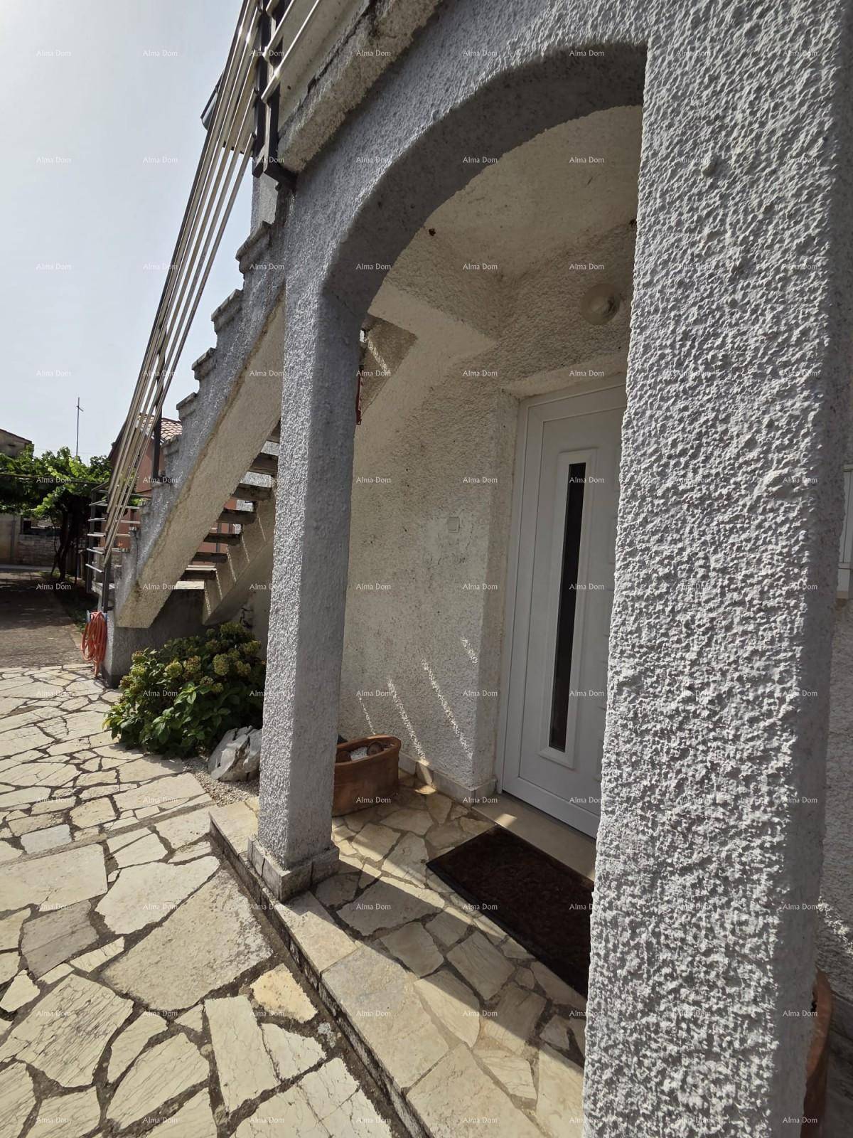 Eingangsbereich des Hauses mit Steinfliesen, gewölbtem Durchgang und weißer Eingangstür.