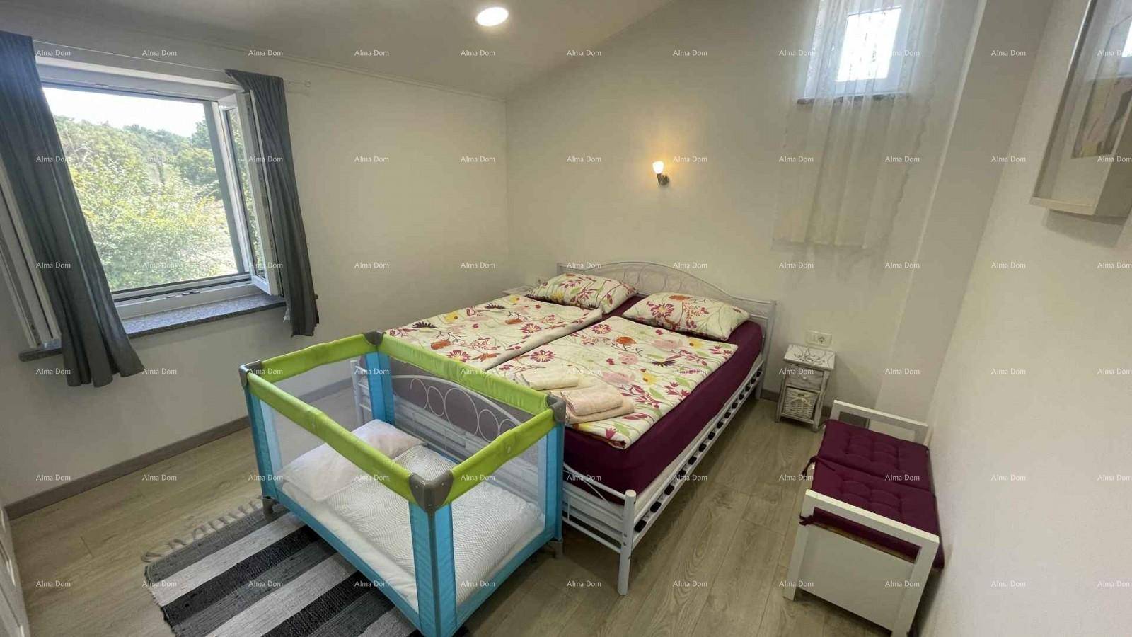 Helles Schlafzimmer mit Doppelbett, Babybett und Blick ins Grüne durch das Fenster.