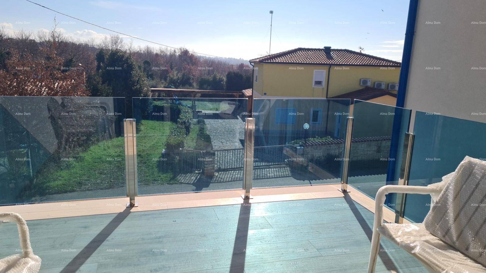 Heller Balkon mit Glasgeländer, Sitzgelegenheiten und Blick auf die grüne Umgebung.