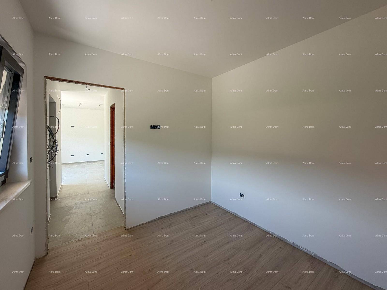 Leeres Zimmer mit Laminatboden und weiß gestrichenen Wänden, mit Zugang zu einem weiteren Raum.