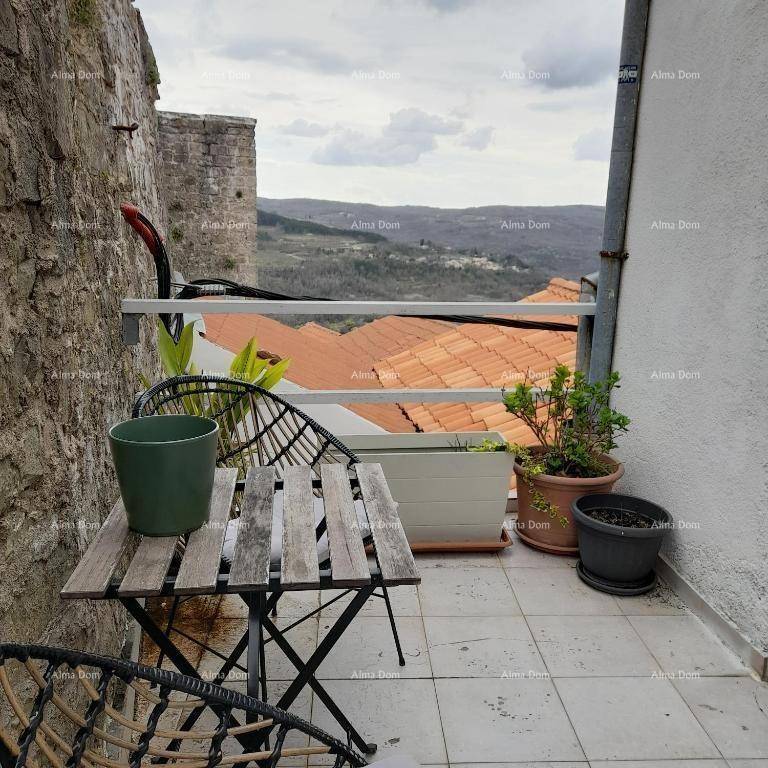 Kleiner Balkon mit Tisch und Stühlen, umgeben von Steinmauern und Blick auf die Landschaft.