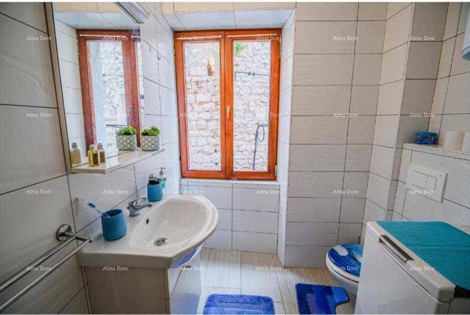 Modernes Badezimmer mit weißen Fliesen, Fenster und einem Waschbecken mit Unterschrank.