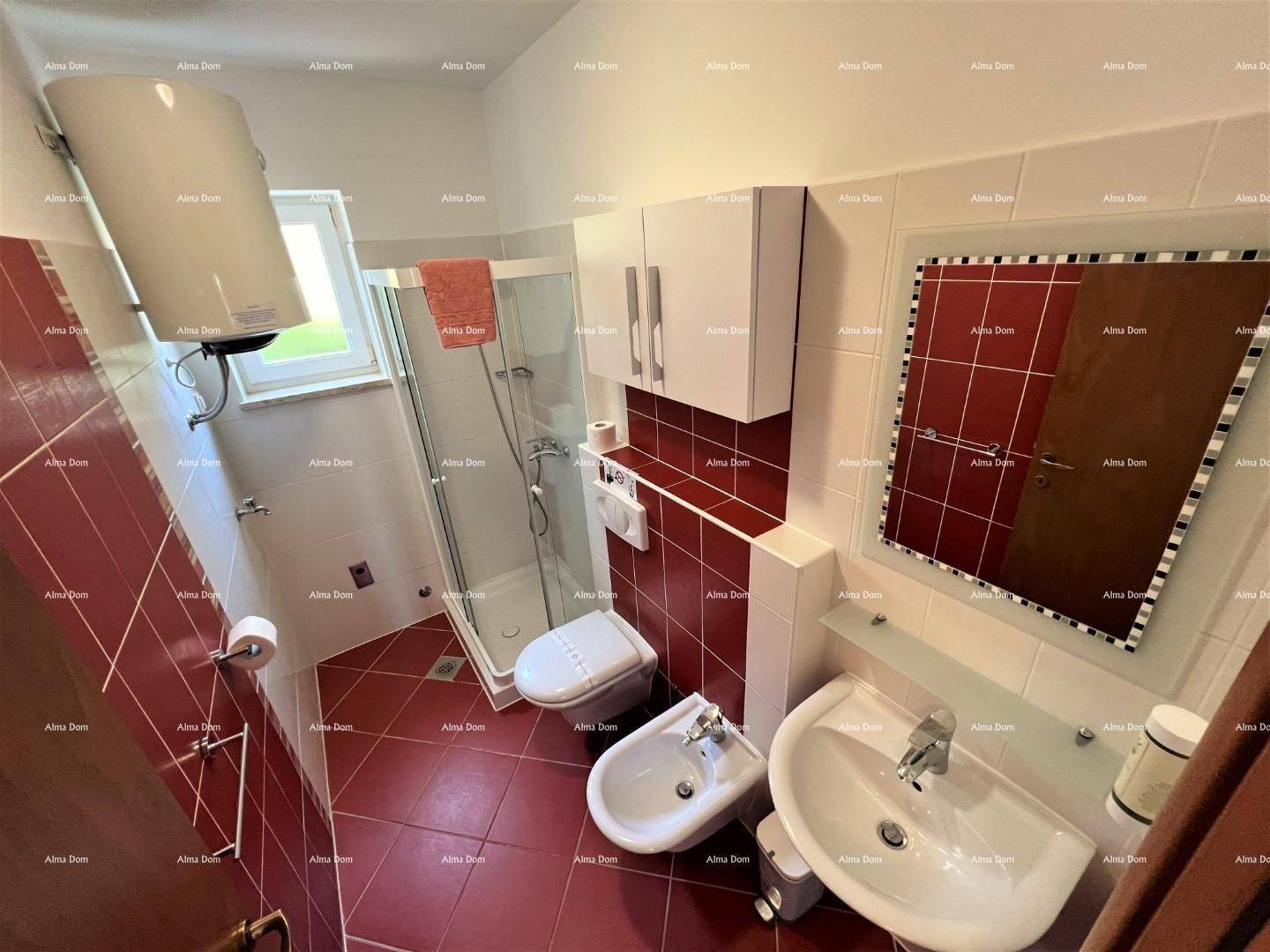 Funktionales Badezimmer mit roten und weißen Fliesen, Dusche, WC, Bidet und Fenster.