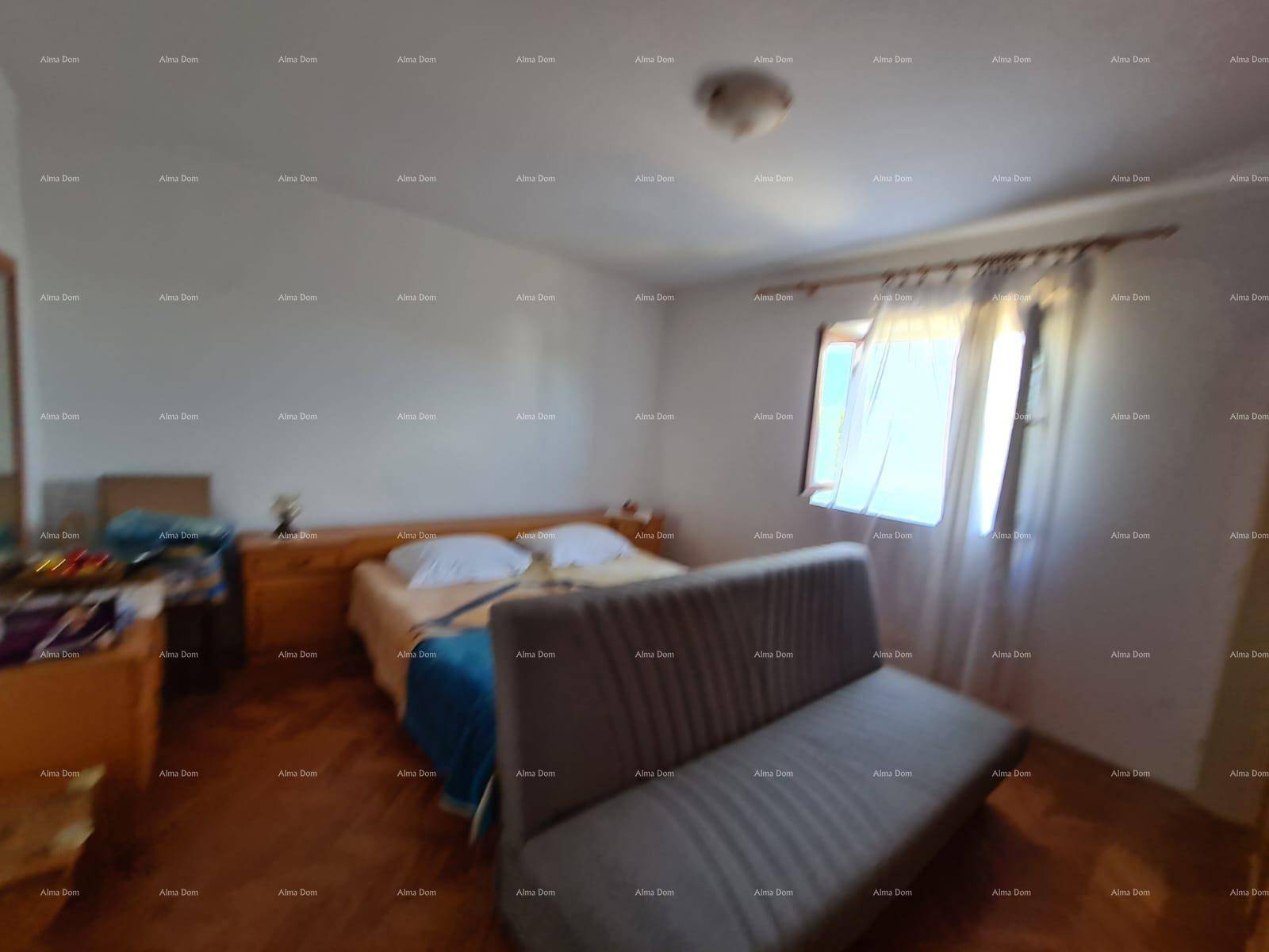 Schlafzimmer mit Holzboden, einem Bett und einem Sofa, das als zusätzliche Sitzgelegenheit dient.