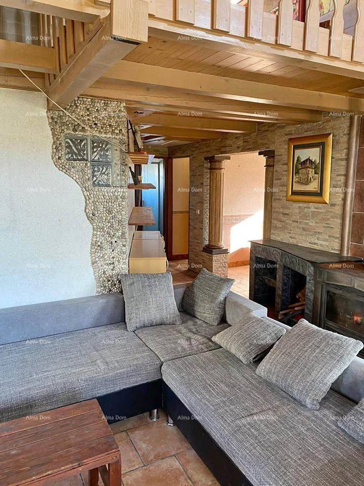 Rustikales Wohnzimmer mit Ecksofa, Kamin und sichtbaren Holzbalken sowie einer Holztreppe.