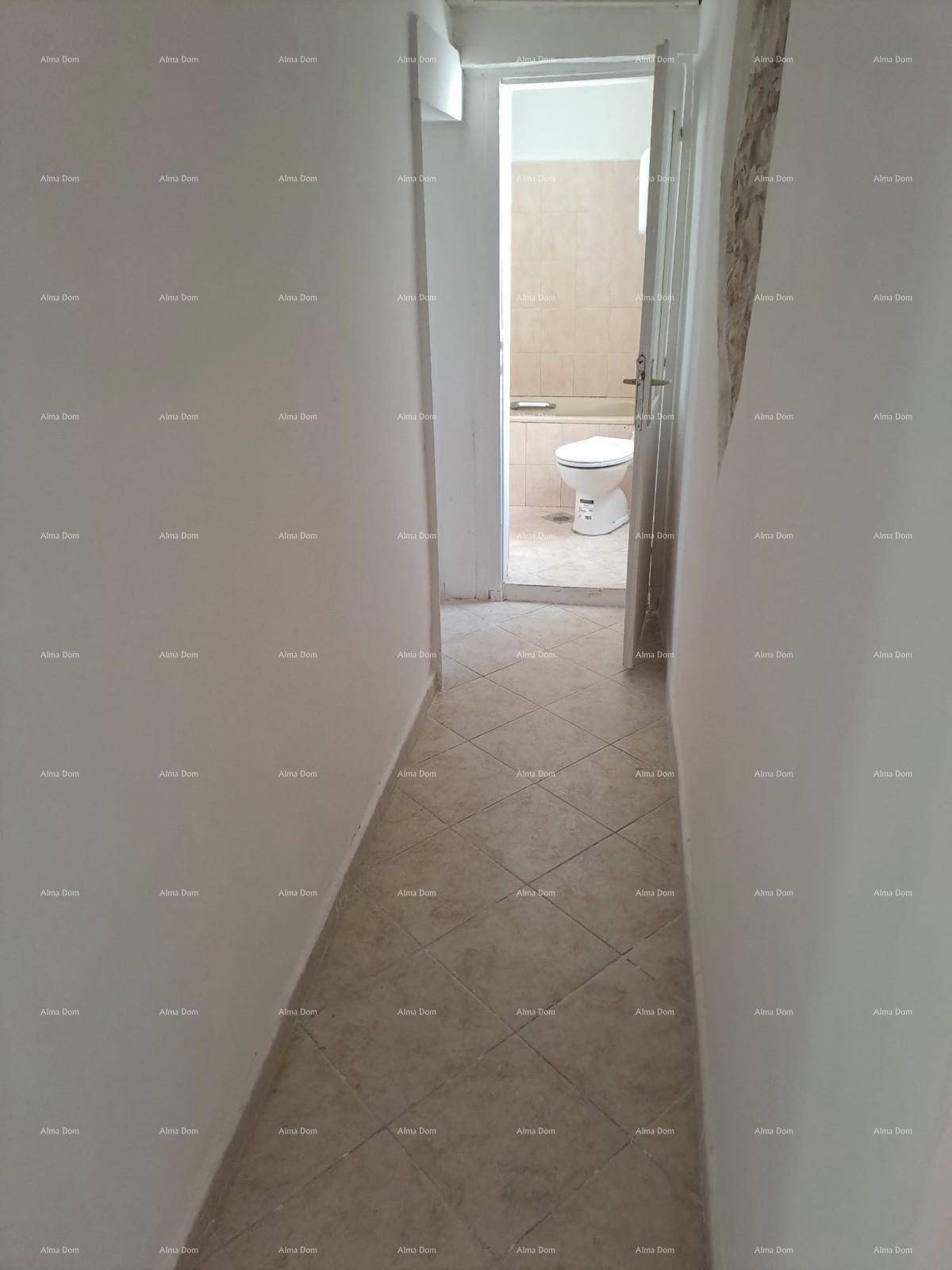 Langer Flur mit Fliesenboden, der zu einem Badezimmer mit Toilette führt.