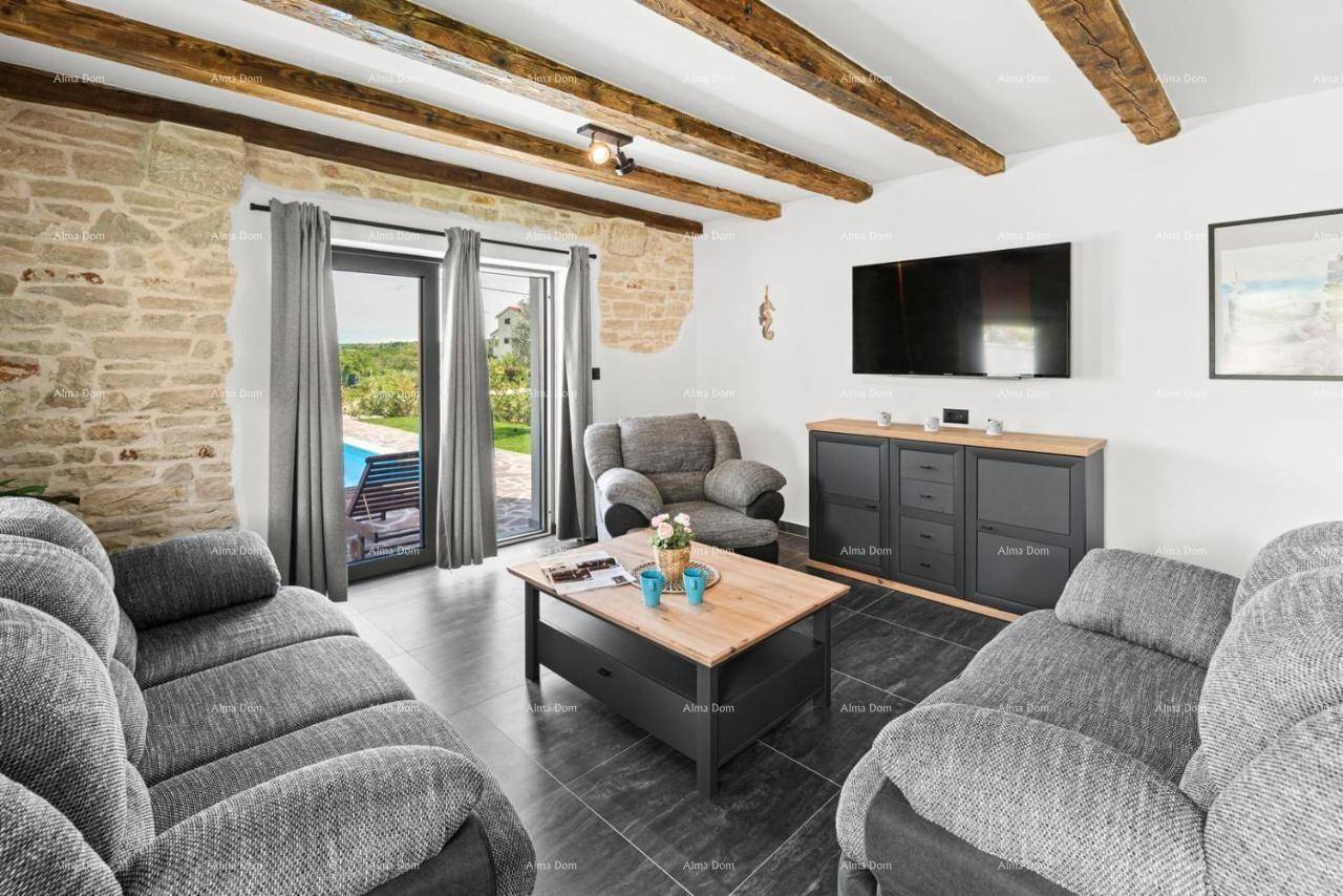 Wohnzimmer mit grauen Sofas, TV und großer Glastür, die einen schönen Blick auf den Außenbereich mit Pool bietet.