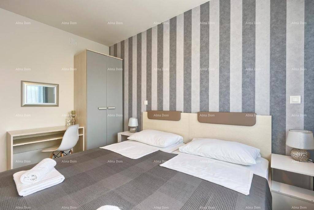 Gemütliches Schlafzimmer mit Doppelbett, gestreifter Wand und praktischem Schreibtisch.