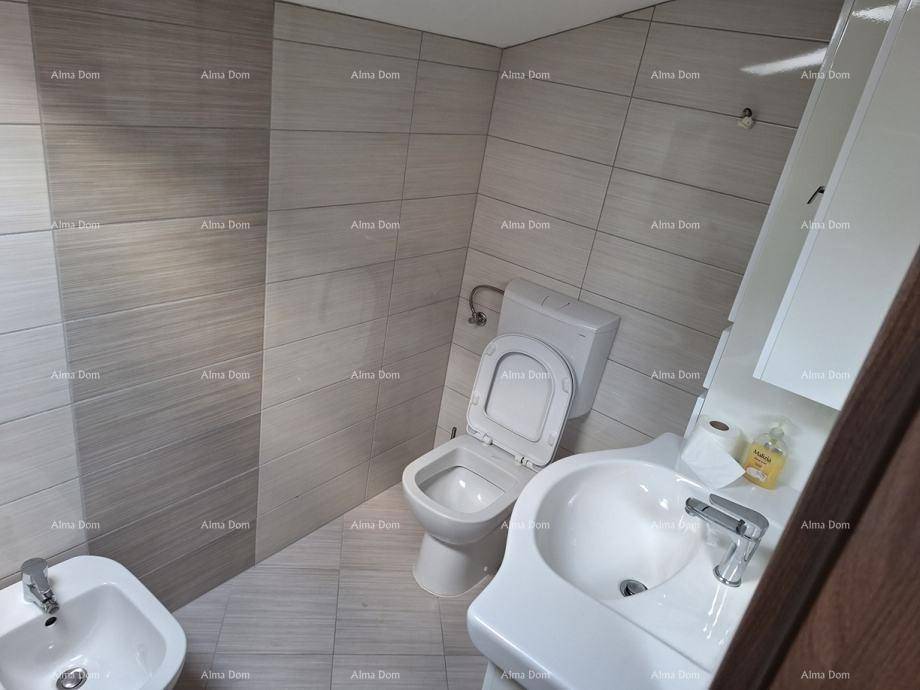 Modern gefliestes Badezimmer mit Toilette, Waschbecken und Bidet in hellen Grautönen.