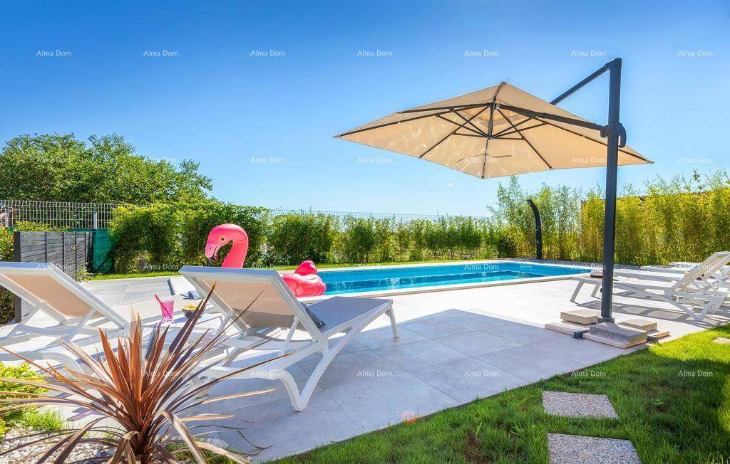Sonniger Poolbereich mit Liegestühlen, großem Sonnenschirm und üppiger grüner Bepflanzung im Hintergrund.