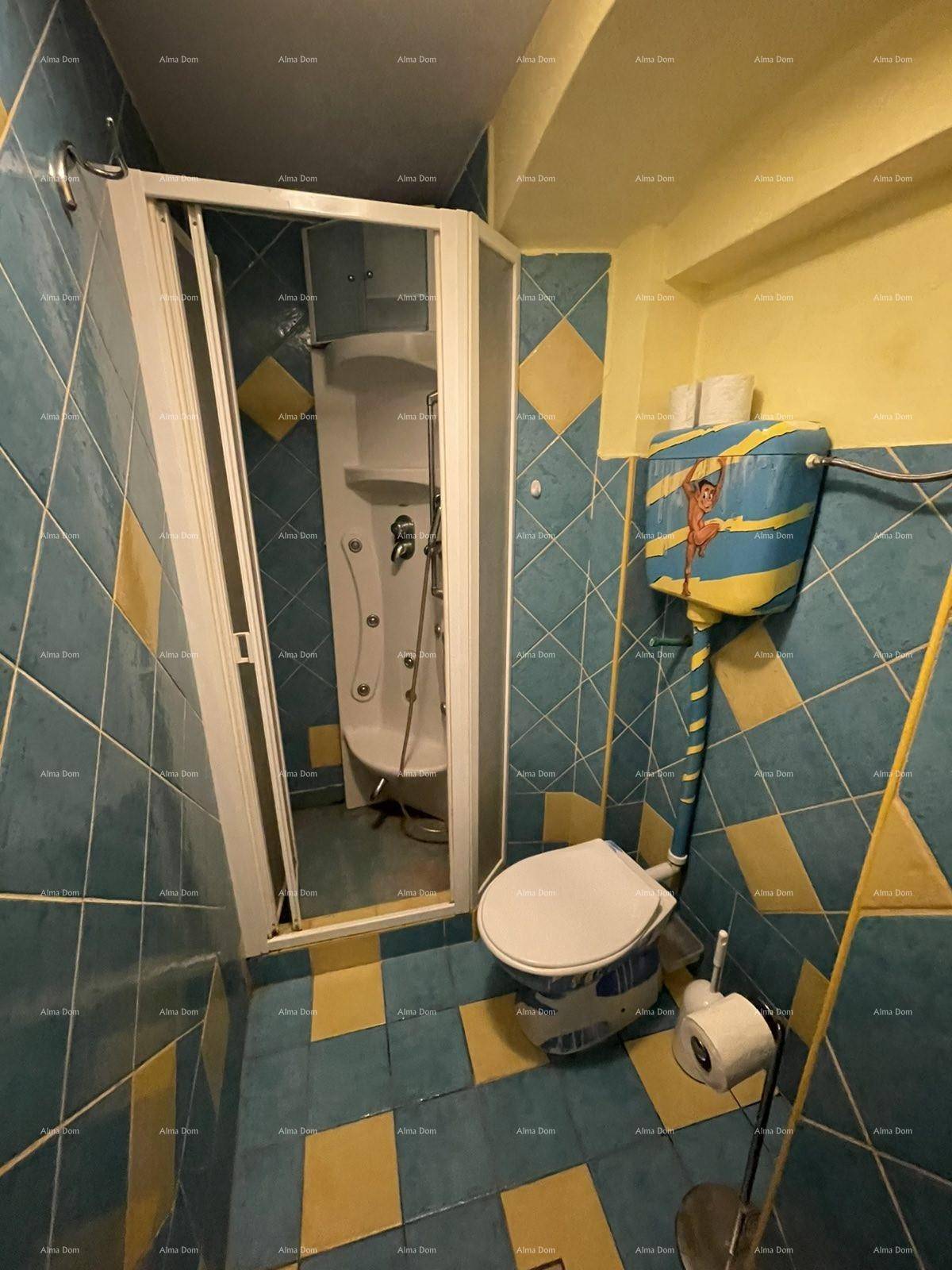 Duschkabine und Toilette in einem Badezimmer mit markanten blau-gelben Fliesen.