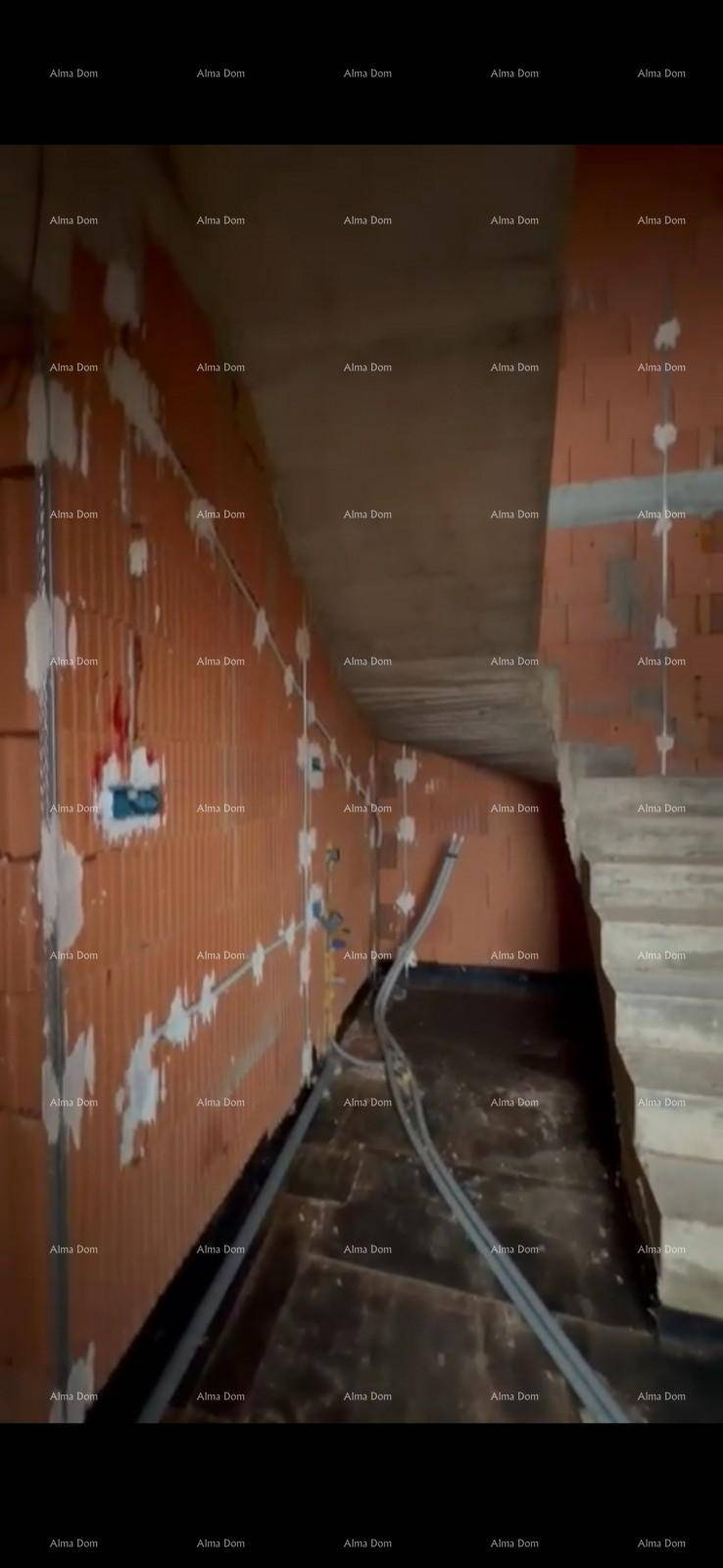 Rohbau-Innenraum mit sichtbarer Betontreppe und unverputzten Ziegelwänden.