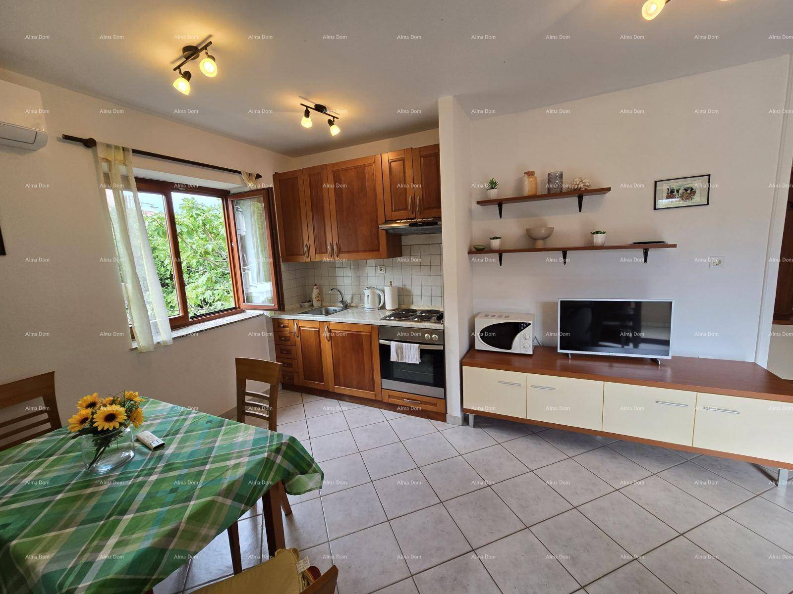 Funktionale Küche mit Holzschränken, Gasherd, Essbereich und Blick ins Grüne durch das Fenster.