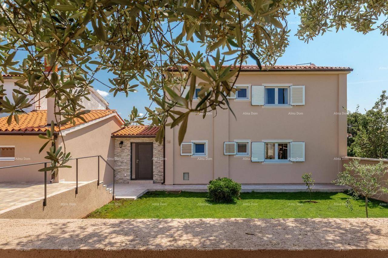 Vorderansicht des Hauses mit Eingangsbereich, gepflegtem Rasen und mediterraner Bepflanzung.