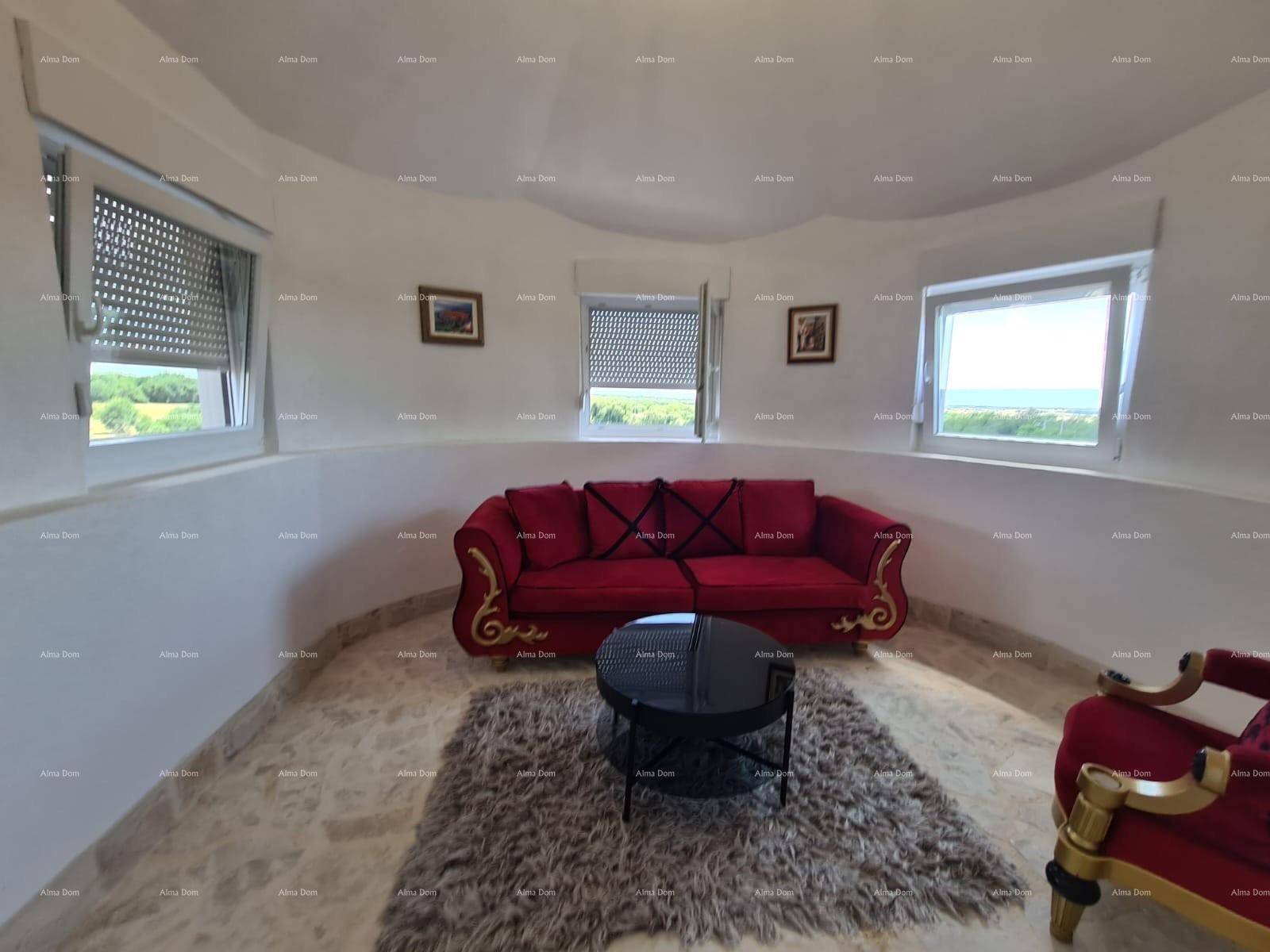 Rundes Wohnzimmer mit rotem Sofa, Teppich und weitem Blick auf die Umgebung.