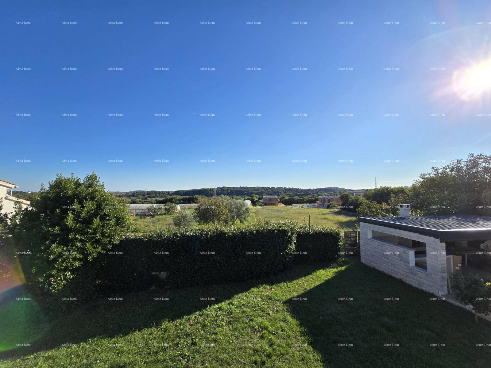 Weite grüne Aussicht über die Landschaft mit Hecken und Bäumen unter blauem Himmel.