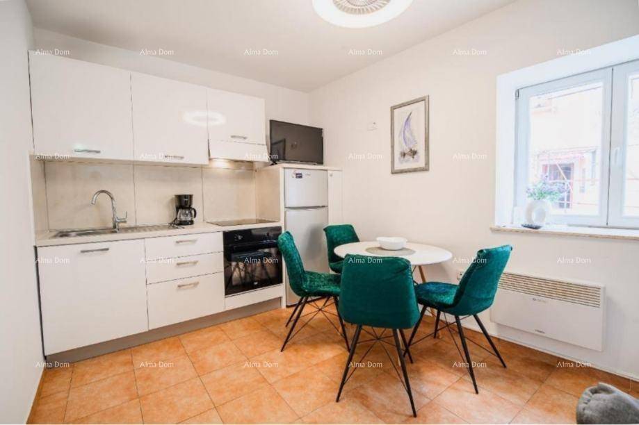 Moderne weiße Küche mit Essbereich, ausgestattet mit einem kleinen Tisch und grünen Stühlen.