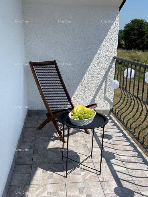 Kleiner Balkon mit Fliesenboden, einem Liegestuhl und einem Beistelltisch mit Obst.