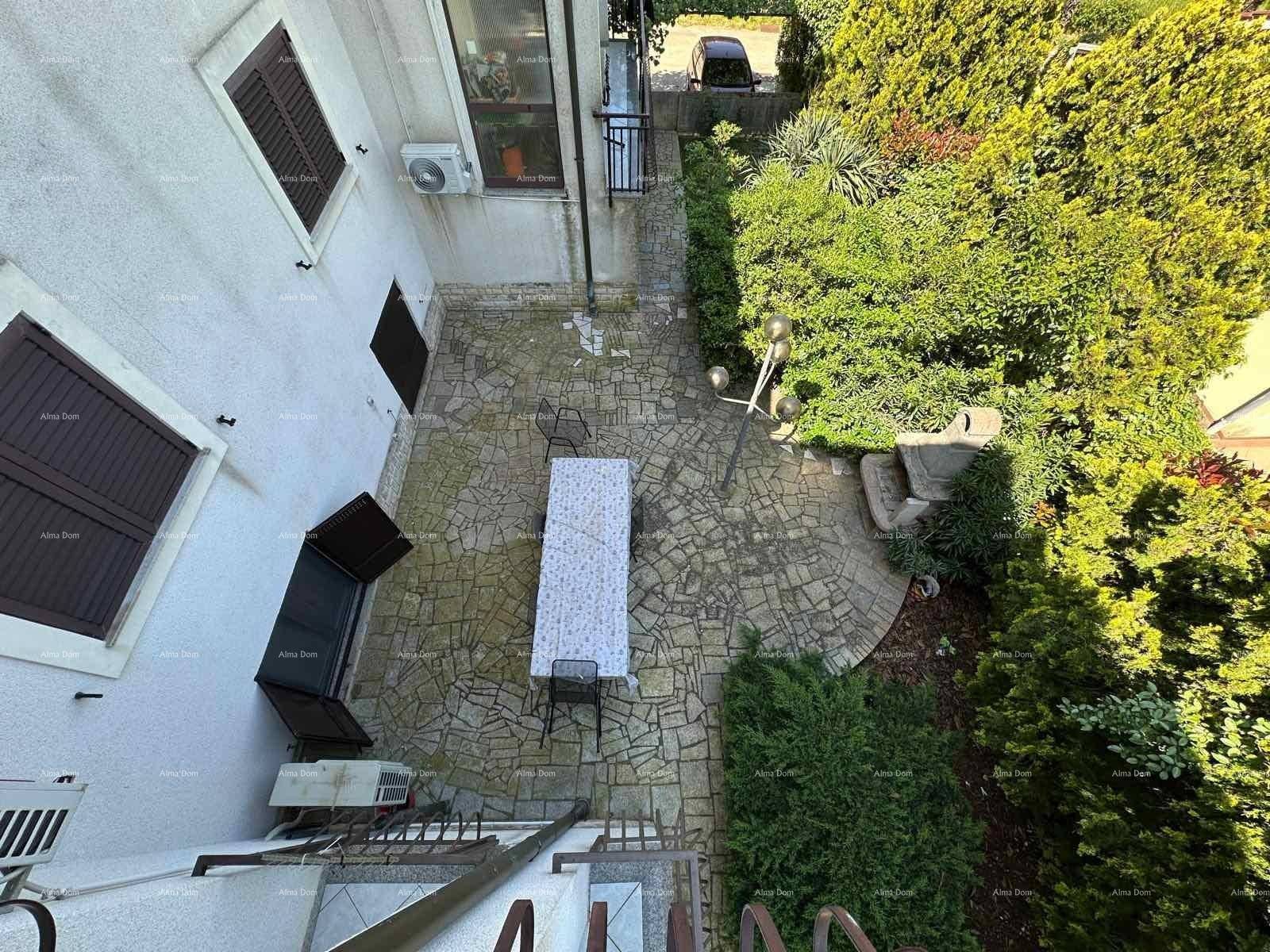 Gemütliche gepflasterte Terrasse mit Tisch und Stühlen, umgeben von üppigem Grün und Sträuchern.