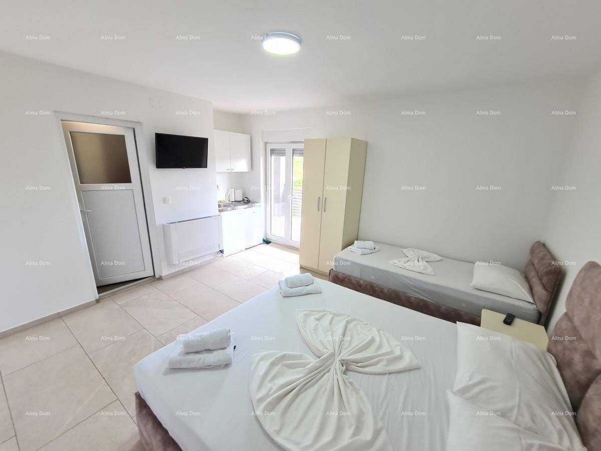 Geräumiges Schlafzimmer mit Doppelbett, Einzelbett und kleiner Küchenzeile.
