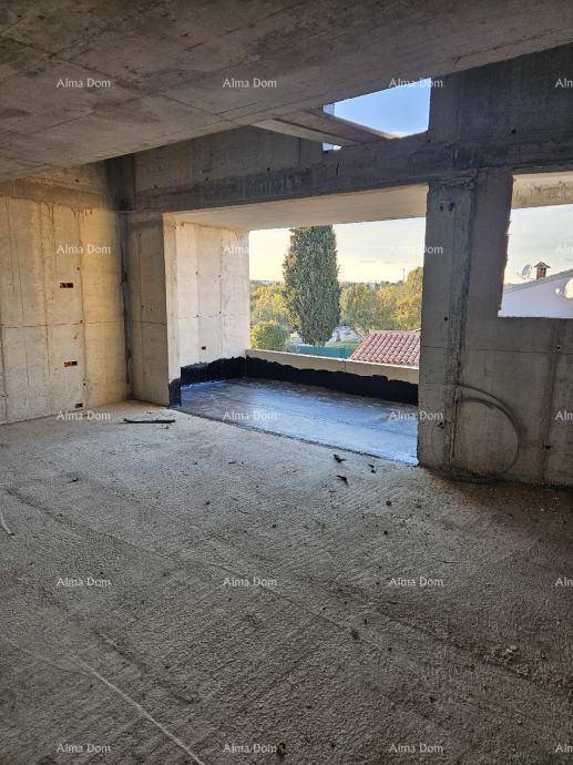 Rohbau eines Raumes mit Betonwänden und großer Öffnung zu einem im Bau befindlichen Außenbereich.
