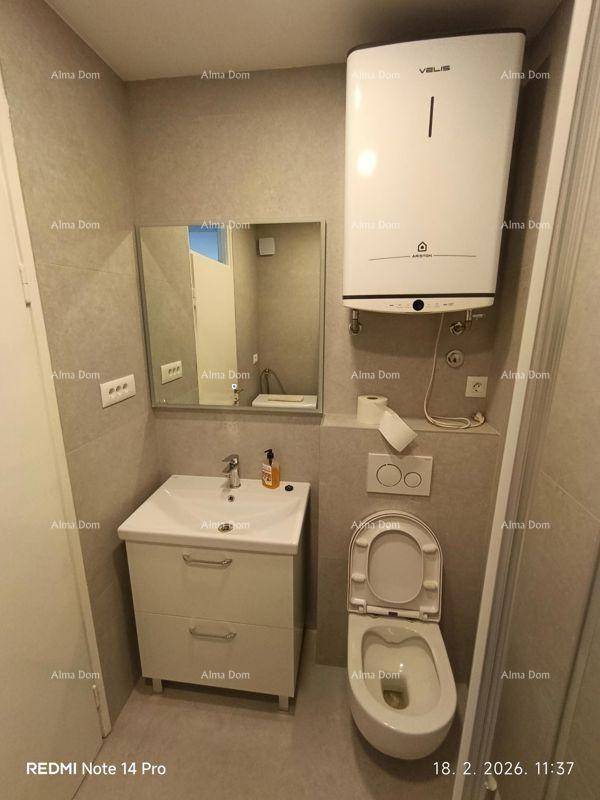 Badezimmer mit WC, Waschbecken mit Unterschrank, Spiegel und Warmwasserboiler.