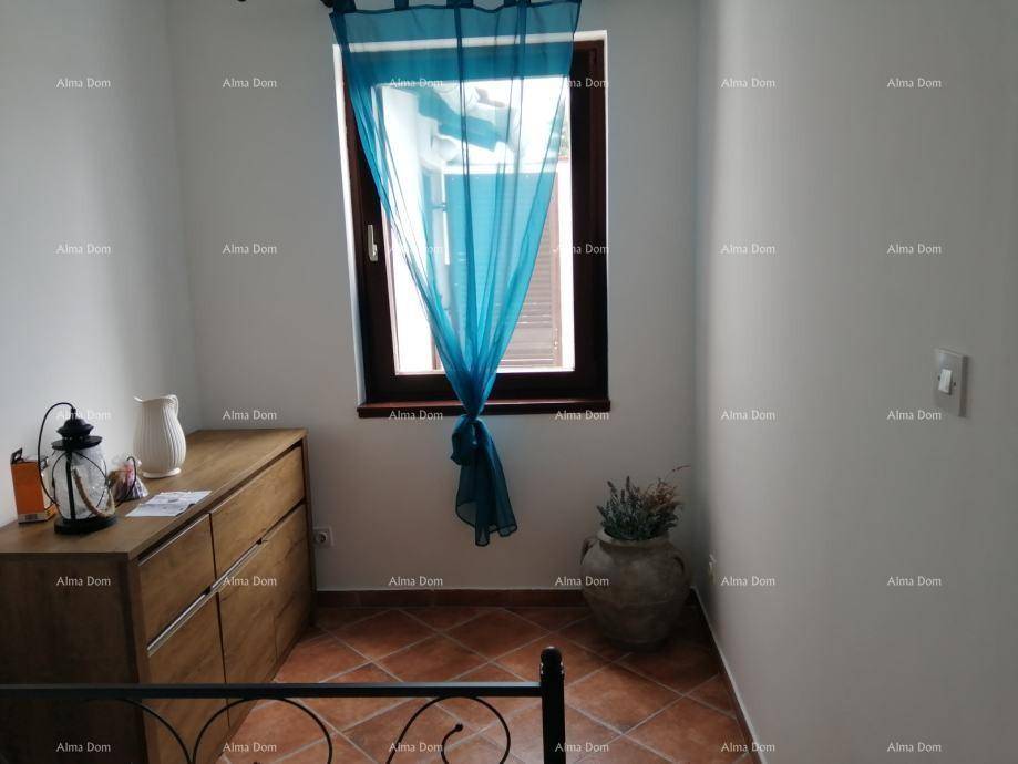 Helles Schlafzimmer mit Holzkommode, Fenster und terracottafarbenem Fliesenboden.