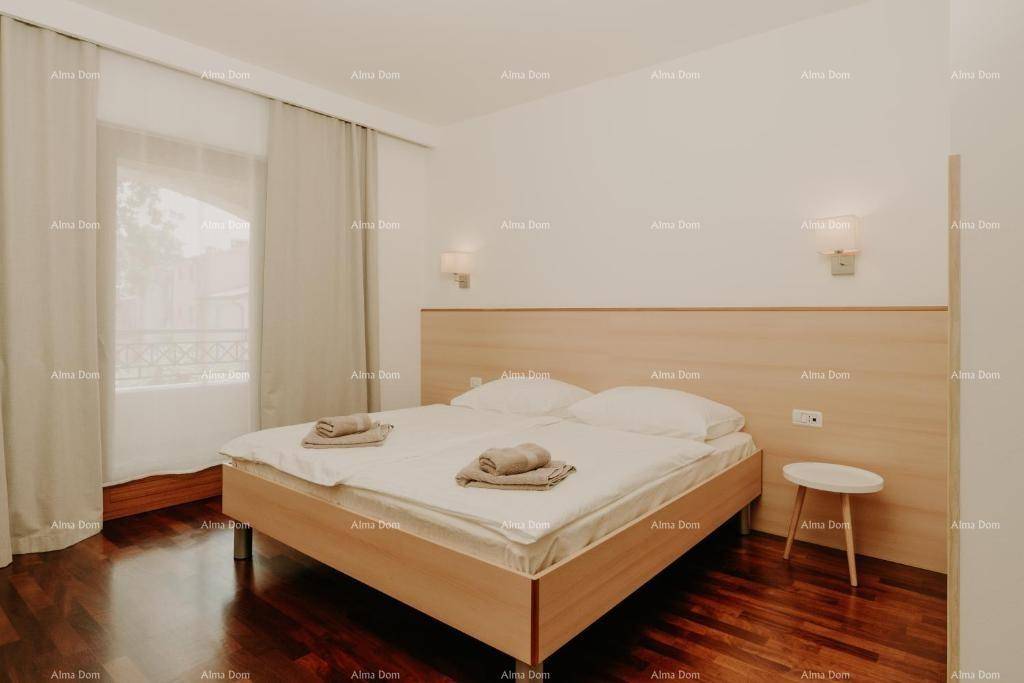 Helles Schlafzimmer mit Doppelbett, Holzboden und großem Fenster, das viel natürliches Licht hereinlässt.