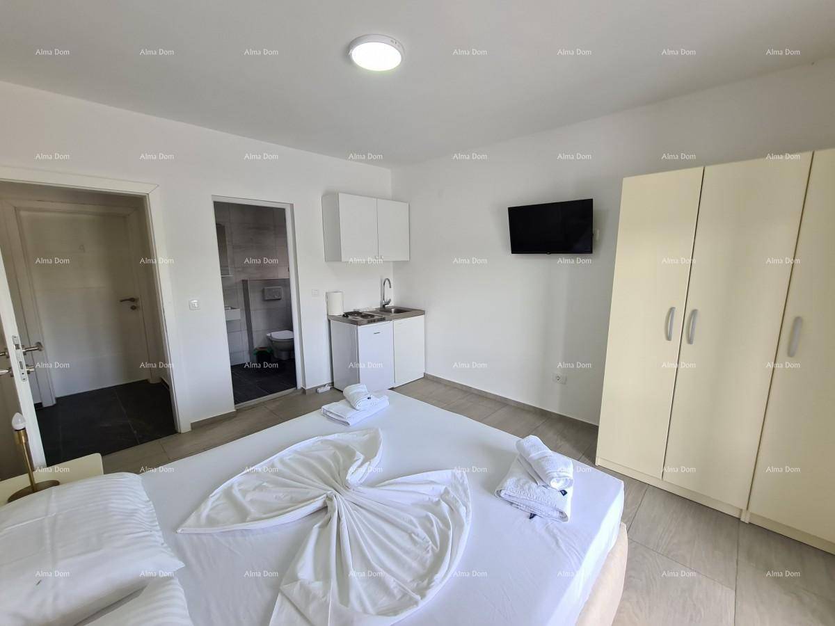 Schlafzimmer mit Doppelbett, Kleiderschrank und integrierter Küchenzeile, daneben ein Badezimmer.