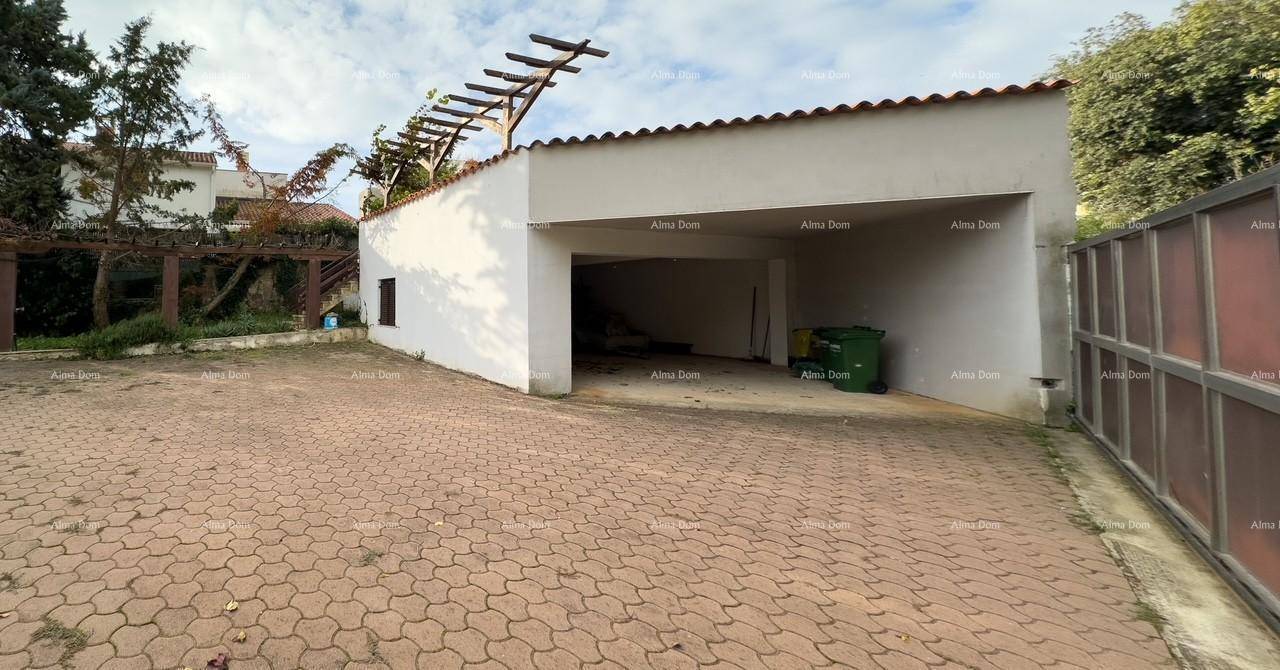 Offene Garagenzufahrt mit Blick in den leeren Garagenraum und einem Mülleimer, daneben gepflasterter Bereich.