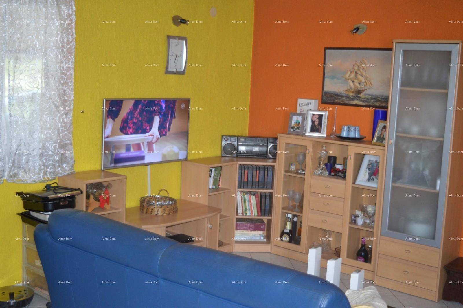 Farbenfrohes Wohnzimmer mit gelben und orangen Wänden, Fernseher und Regalsystem.