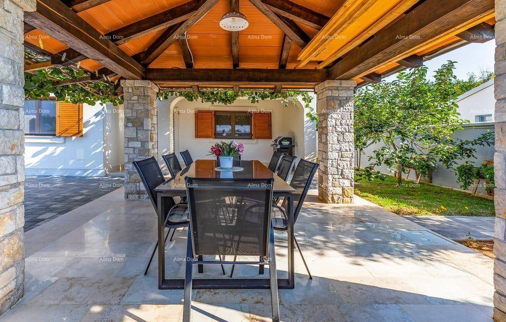 Gemütlicher Essbereich im Freien unter einer Pergola mit Holzbalken und Steinsäulen, ideal für Mahlzeiten.