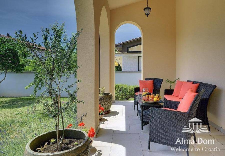 Gemütliche überdachte Terrasse mit bequemen Sitzgelegenheiten und Blick auf den Garten.