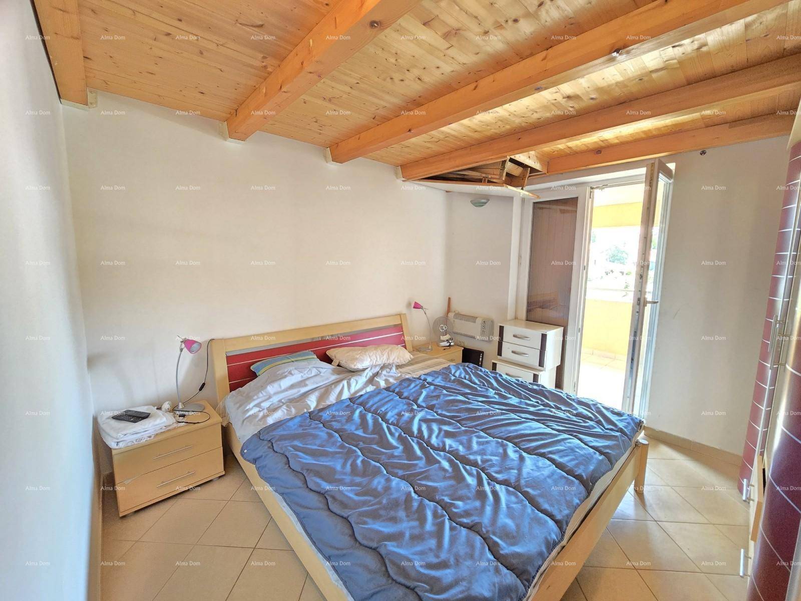 Schlafzimmer mit Holzbalkendecke, Fliesenboden und Zugang zu einem Balkon.