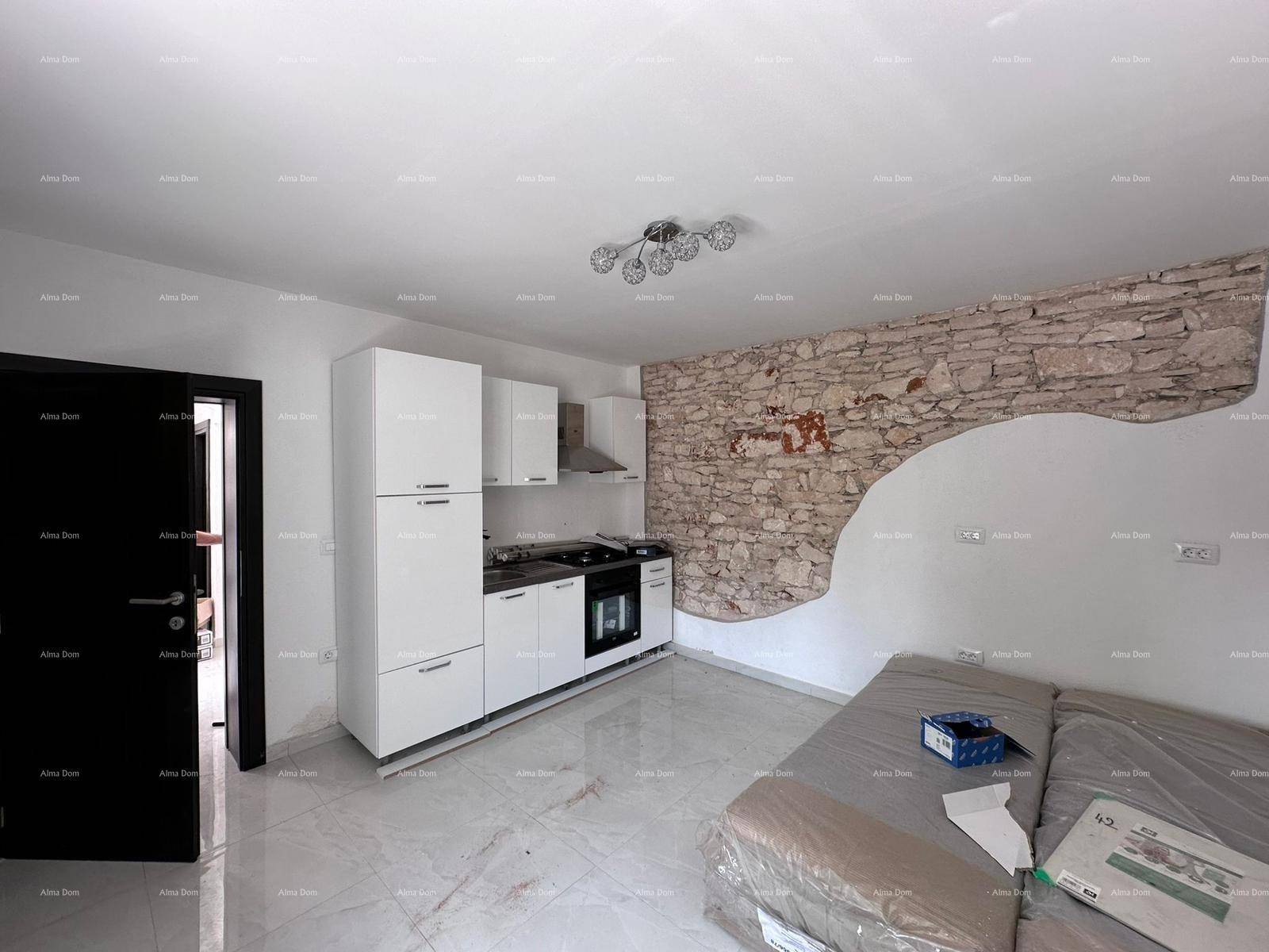 Moderne Küche mit weißen Schränken, freigelegter Steinwand und einem Sofa.