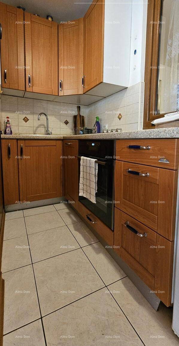 Funktionale Küche mit Holzschränken, Fliesenboden und integriertem Backofen.